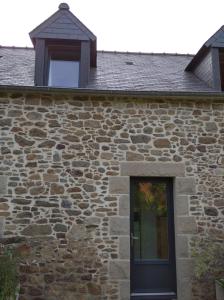 a stone building with a black door and a window at Charmant Appartement in Saint Malo