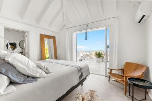 a white bedroom with a bed and a view of the ocean at Magnifique villa 3 chambres sur les hauteurs de Grand Case in Saint Martin