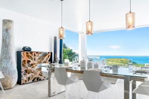 ein Esszimmer mit einem Tisch, Stühlen und Meerblick in der Unterkunft Grand Case - Villa chic 6p 3ch 3sdb Vue panoramique in Saint Martin