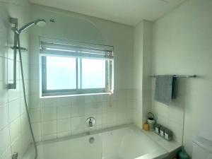 baño blanco con bañera y ventana en Devine Stay, en Paarl