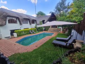 a house with a swimming pool and an umbrella at 60 on Monica, 6 Bedroom Lesedi Lodge, Hartbeespoort in Hartbeespoort