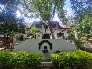 une maison blanche avec un arbre en face dans l'établissement 60 on Monica, 6 Bedroom Lesedi Lodge, Hartbeespoort, à Hartbeespoort