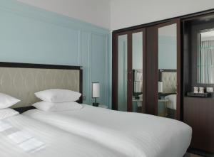 فندق ماريوت أمباسادور باريس أوبرا في باريس: غرفة نوم بسرير كبير عليها شراشف ووسائد بيضاء