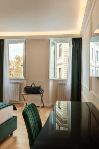 a living room with a glass table and green chairs at Relais del Portico in Rome