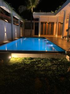 a large blue swimming pool in a house at night at Eton Villa in Dickwella