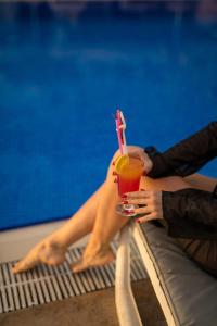 une personne assise dans une piscine pour boire un verre dans l'établissement Sunset Beach Club Aqua Lettings, à Fethiye