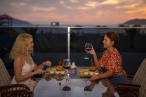 twee vrouwen aan een tafel met een glas wijn bij Sunset Beach Club Aqua Lettings in Fethiye