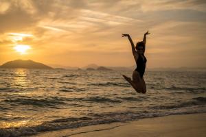 Une femme sautant en l'air sur la plage dans l'établissement Sunset Beach Club Aqua Lettings, à Fethiye