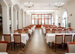 uma sala de jantar com mesas e cadeiras brancas em Hotel Magellan em Bronisławów