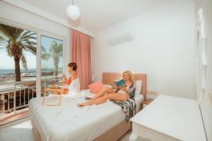 twee vrouwen op een bed in een hotelkamer bij Sunset Beach Club Aqua Lettings in Fethiye