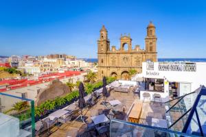 a balcony with tables and chairs in front of a church at Boutique Hotel Cordial Plaza Mayor de Santa Ana in Las Palmas de Gran Canaria