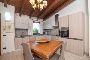 uma cozinha com uma mesa de madeira com cadeiras e um lustre em Residenza del golfo em Telti