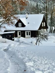 a house is covered in snow with a trail at Chaloupka Dvě Sestry in Kořenov