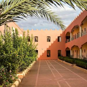 une cour d'un bâtiment avec des arbres et des buissons dans l'établissement Hôtel Relais Saiss, à Séfrou