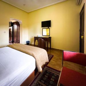 a bedroom with a bed and a desk with a television at H&ocirc;tel Relais Saiss in Sefrou