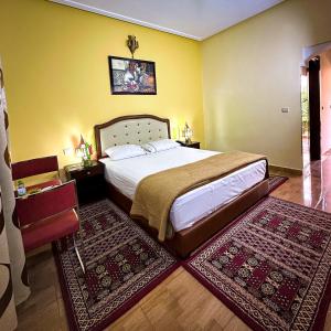 a bedroom with a large bed and two rugs at Hôtel Relais Saiss in Sefrou