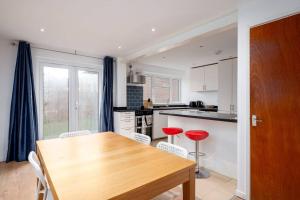 a kitchen with a wooden table and red chairs at GuestReady - Tranquil Retreat near the Royal Docks in London