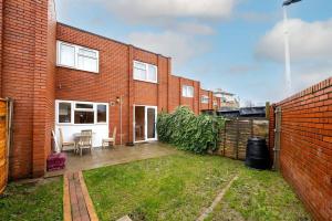 a brick house with a yard with a fence at GuestReady - Tranquil Retreat near the Royal Docks in London