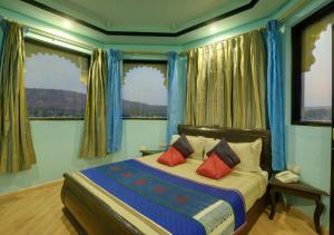 a bedroom with a bed with blue walls and windows at jüSTa Lake Nahargarh Palace, Chittorgarh in Pārsoli