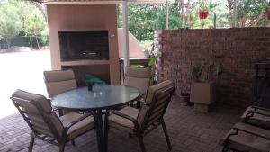 patio con mesa, sillas y TV en Lily Guesthouse, en Bloemfontein