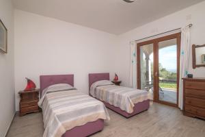 Appartamento Bellavista في Telti: سريرين في غرفة بيضاء مع باب زجاجي منزلق