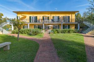 une maison jaune avec une passerelle en briques devant elle dans l'établissement Residence gli Olmi - Goelba, à Marina di Campo