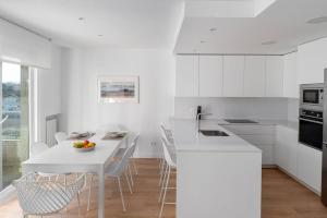 a white kitchen with a white table and chairs at Bright apartment with A/C, parking optional in San Sebastián