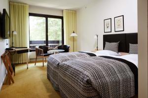 a bedroom with two beds and a desk and a window at Munkebjerg Hotel in Vejle