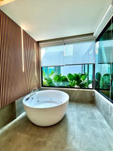 a large white tub in a room with a large window at Rock Resort Ratchaburi in Ratchaburi
