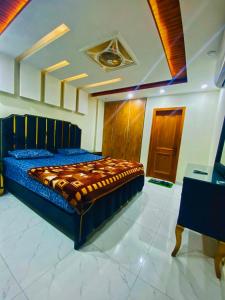 a bedroom with a bed with a blue comforter at Luxury Apartment in Bahria Town, Lahore in Lahore