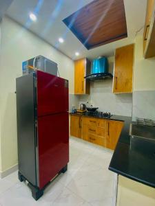 a kitchen with a red refrigerator and wooden cabinets at Luxury Apartment in Bahria Town, Lahore in Lahore