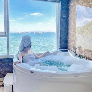 uma mulher numa banheira com uma janela em Aquamarine Premium Cruise em Ha Long