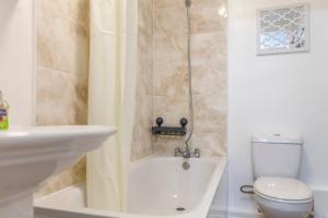 a bathroom with a tub and a toilet and a sink at Amazing 1 BR apartment, Barons Court in London