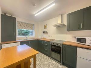 a kitchen with green cabinets and a wooden table at A modern one bed 1st floor apartment, Lichfield in Lichfield