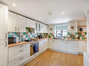 a large kitchen with white cabinets and a window at 3 Bed in Exeter KENCI in Clyst Saint Mary