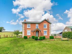 a brick house on a field with a grass yard at 4 Bed in Welshpool 89012 in Llanfair Caereinion