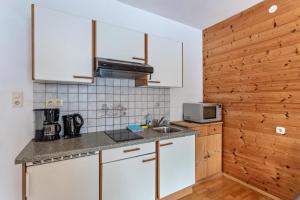 a small kitchen with white cabinets and a sink at Schwüwong - Apartment 02 in Kelchsau