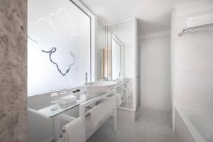 ein weißes Badezimmer mit einem Waschbecken und einem Spiegel in der Unterkunft Falkensteiner Hotel Adriana - Adults Only in Zadar