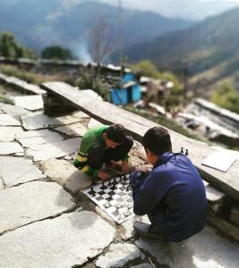two people playing a game of chess on a rock wall at Shri Timli Mountain Village Stay in Dwārīkhāl