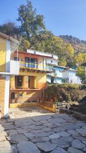 a yellow house with a balcony on a hill at Shri Timli Mountain Village Stay in Dwārīkhāl