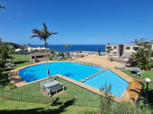 a swimming pool with benches and the ocean in the background at Ripple in time - 4 Adults & 2 kids Only in Umdloti