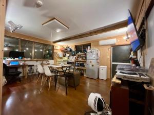 cocina y comedor con mesa y nevera en 奄美ゲストハウス HUB a nice INN, en Setouchi