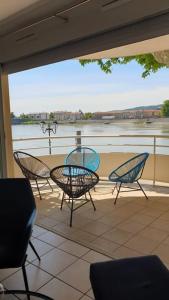 un patio con sillas y una mesa con vistas al agua en Blue**** Vue exceptionnelle sur le Rhône, en Tain-lʼHermitage