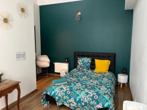 a bedroom with a bed with a blue wall at les Pastoureaux in Orléans
