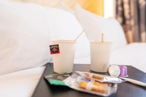 a table with two styrofoam cups on a bed at B&B HOTEL Villefranche-sur-Saône Sud in Villefranche-sur-Saône