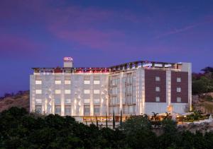 a large white building with a neon sign on top at jüSTa Sajjangarh Resort & Spa, Udaipur in Udaipur