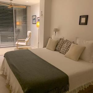 - une chambre avec un grand lit blanc et une chaise dans l'établissement Apartamento sobre el mar, à Salou