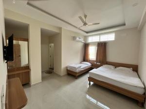 a bedroom with two beds and a television in it at Seema Palace Inn in Mysore