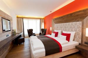 um quarto com uma cama grande e uma parede laranja em Dorfhaus Chalets em Oberstaufen