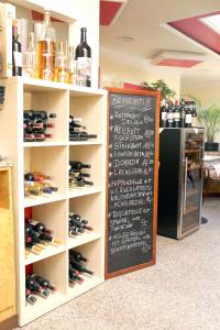 - une étagère avec des bouteilles de vin et un tableau noir dans l'établissement Eiscafe-Pizzeria-Hotel Rialto, à Eilenburg